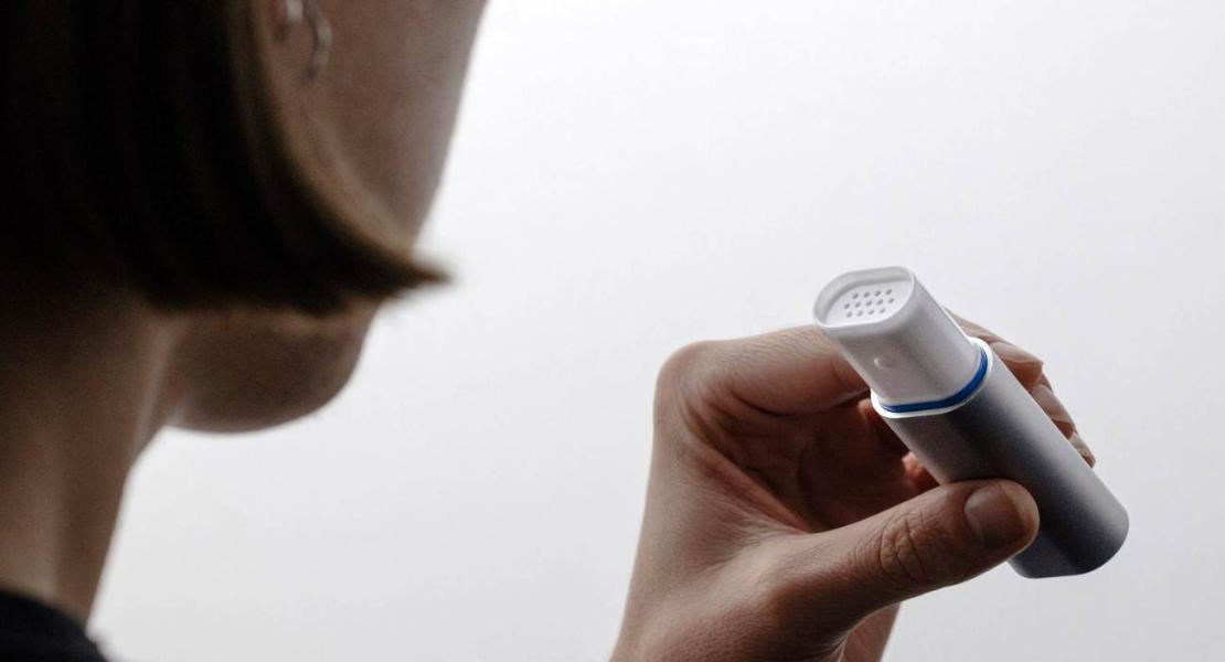 Dispositivo diagnostico modellato su uno spirometro che raccoglie goccioline di aria e saliva dal respiro dell'utente per l'analisi.